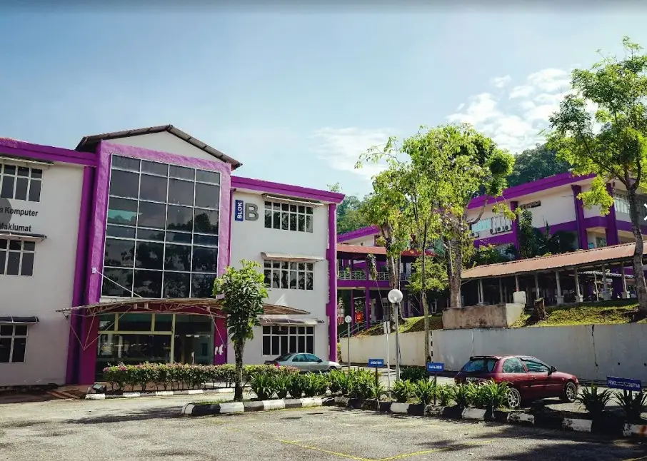 Block B seen from the car park: a three-storey building in purple and white, its name painted beside the tall stairwell windows.